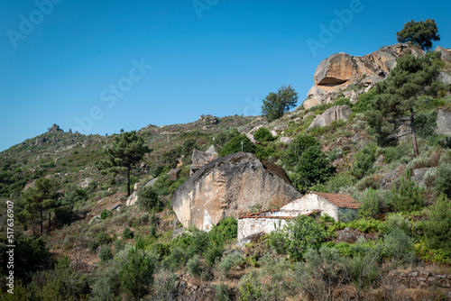 Entre montes, muitas pedras, um pedregulho enorme com uma cruz no topo e uma casa abandonada ao lado photo