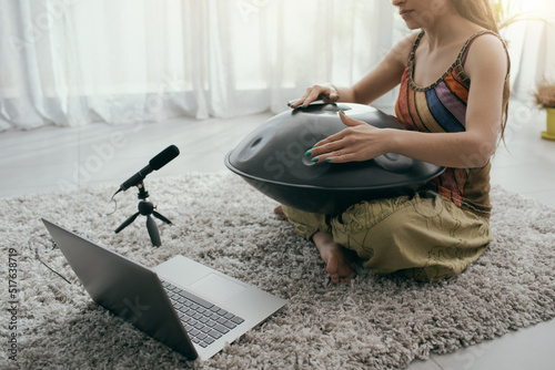 Woman playing a hang drum and recording photo