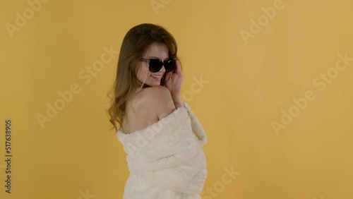 Beautiful sexy girl in a fur coat and sunglasses. She smiles with white teeth
and interesting on isolated background.