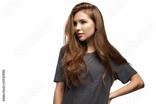 Portrait of attractive young model looking away in studio wearing grey shirt with black space. Luxury brunette hairstyle of pretty girl posing on white background. Fashion and beauty concept