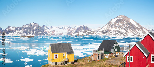 Panoramic view of colorful Kulusuk village in East Greenland - Kulusuk, Greenland - Melting of a iceberg and pouring water into the sea photo