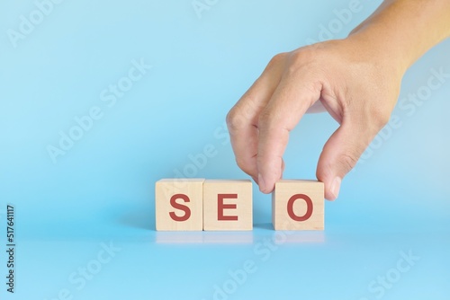Search Engine Optimization or SEO business marketing strategy concept. Human hand stacking wooden blocks.