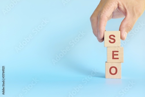 Search Engine Optimization or SEO business marketing strategy concept. Human hand stacking wooden blocks.