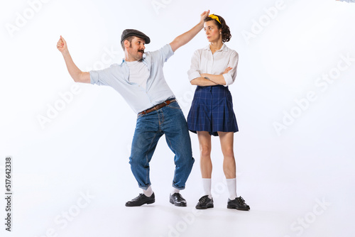 Portrait of young stylish woman looking at dancing cheerful man isolated over white studio background © Lustre