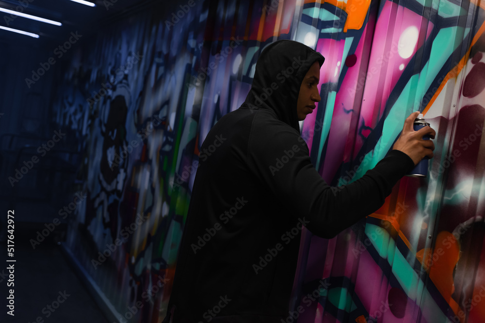 Side view of african american vandal painting graffiti on wall - obrazy, fototapety, plakaty 