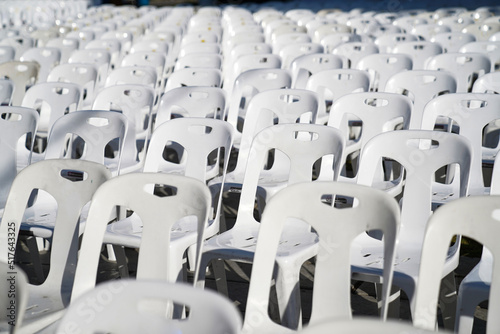 Many white plastic chairs were set up in a square area with the row and column for outdoor concerts or open air events.