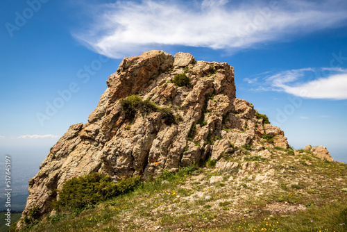 A large boulder on top of 3 brothers, wearing a hat made of clouds., a popular trekking trail near Almaty city.