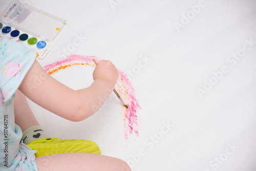 kid painting rainbow, little girl painting colorful rainbow on large sheet of paper