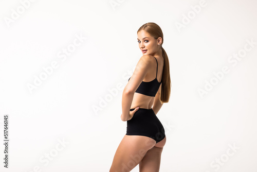Back view of sensual woman wearing black top and thongs, demonstrating perfect strong butt muscles at camera. People, active lifestyle, beauty, sports, fitness and determination concept
