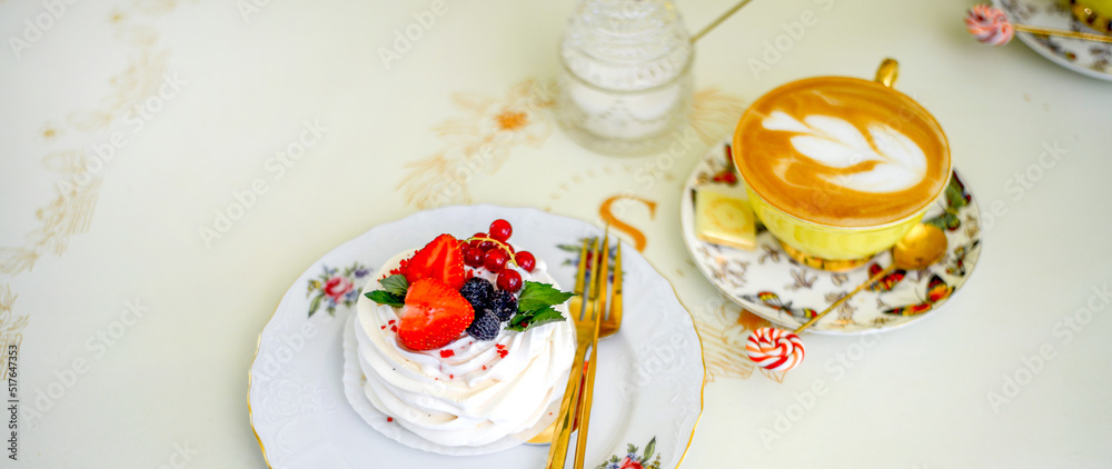 Obraz premium Banner with sweet meringue dessert decorated with strawberries, blackberries and red currants and a cup of coffee. Elegant service. Morning concept.