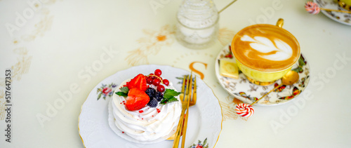 Banner with sweet meringue dessert decorated with strawberries, blackberries and red currants and a cup of coffee. Elegant service. Morning concept.
