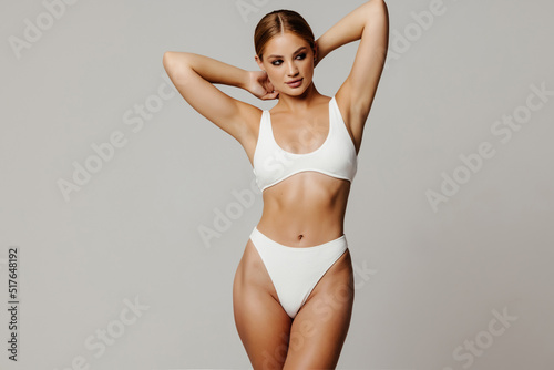 Shows white underwear. Beautiful woman with slim body is in the studio background