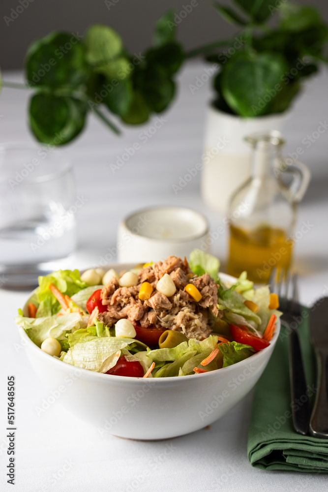 Tuna salad table setting with white , glass of water and olive oil for dressing, and cutlery. Tuna salad table setting with white , glass of water and olive oil for dressing, and cutlery.
