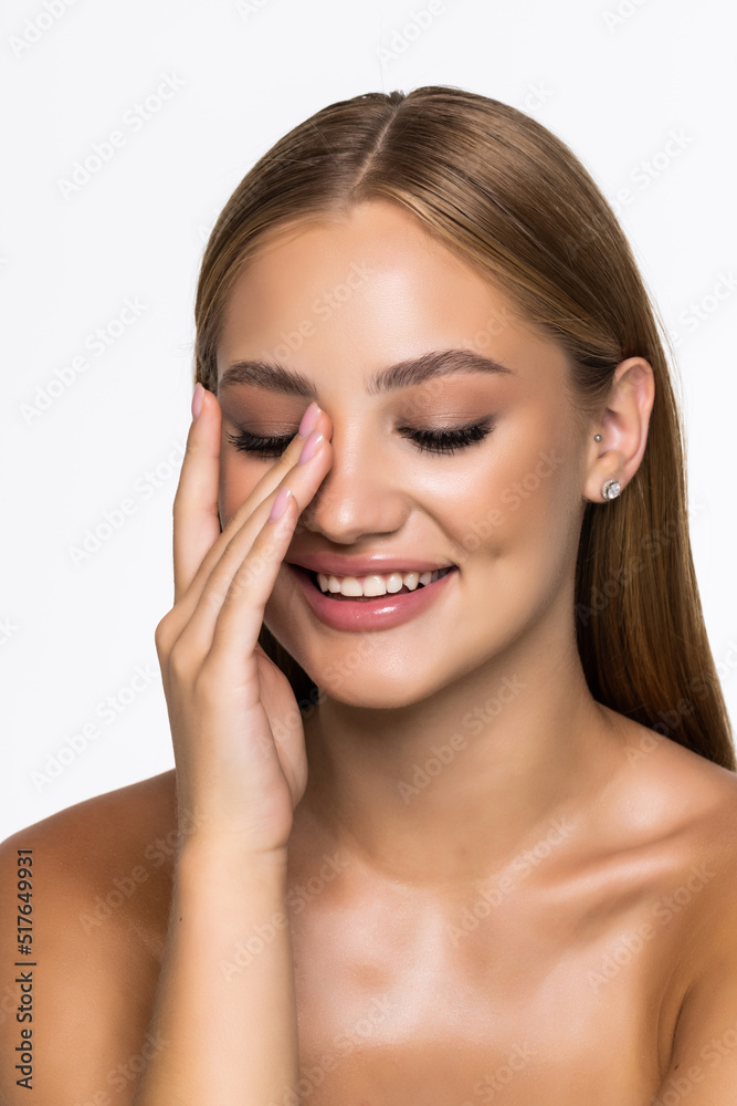 Portrait of smiling beautiful young girl with perfect glowing skin and bare shoulders on white background. Beautiful natural woman looking at camera. Spa, skincare and wellness concept.