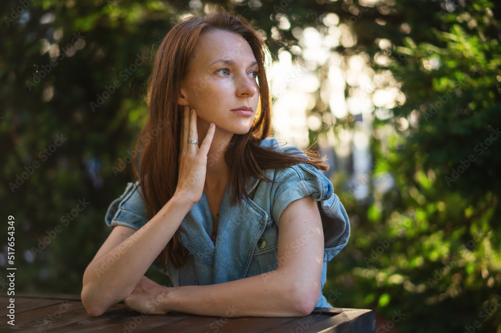 Portrait of a young beautiful red-haired woman sitting on a summer terrace in the city Portrait of a young beautiful red-haired woman sitting on a summer terrace in the city