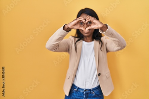 African young woman wearing glasses smiling in love doing heart symbol shape with hands. romantic concept. © Krakenimages.com