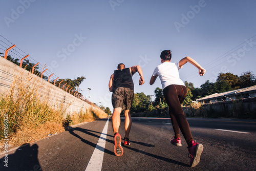 Fotografi Powerful athletic couple runner sprinting together on the road from back view
