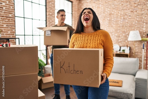 Young couple moving to a new home with cardboard boxes angry and mad screaming frustrated and furious, shouting with anger looking up. © Krakenimages.com