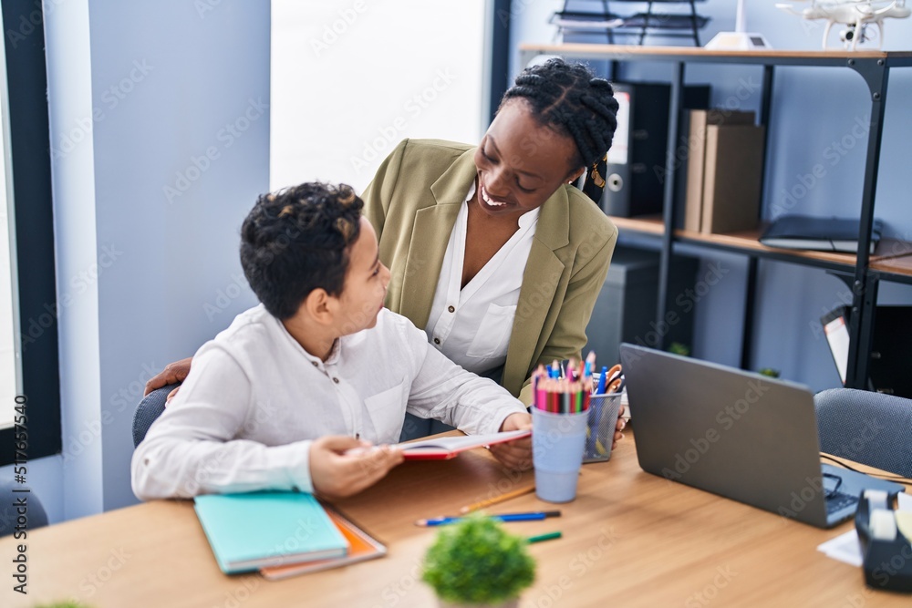 African american mother and son using laptop and reading book at office African american mother and son using laptop and reading book at office