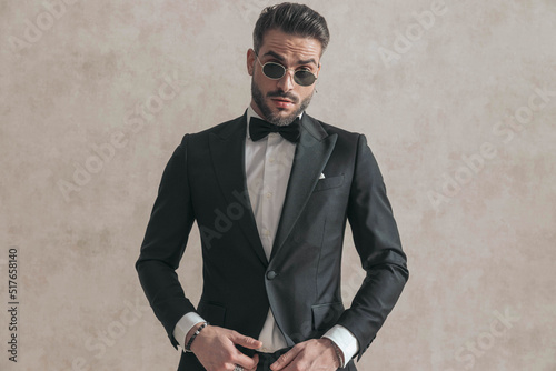Fototapeta elegant businessman in black tuxedo wearing sunglasses and posing
