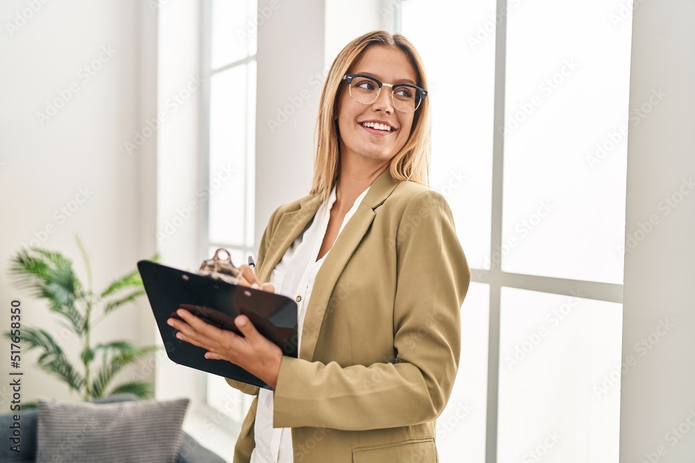 Young hispanic woman psychologist writing mental report standing at psychology center Young hispanic woman psychologist writing mental report standing at psychology center