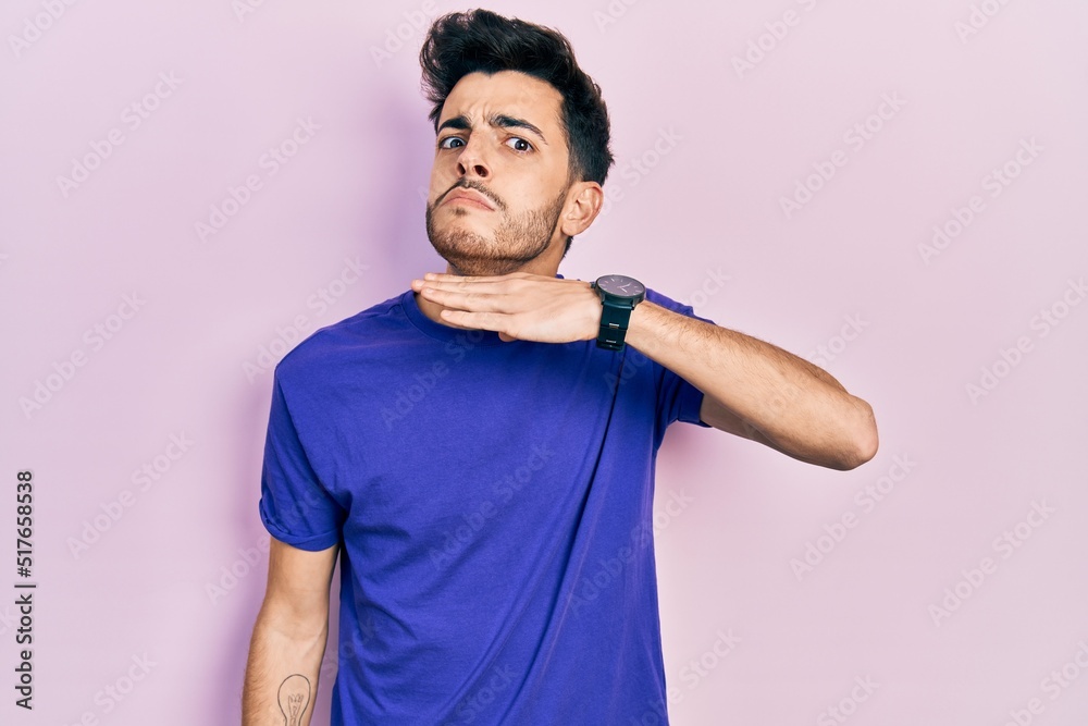 Young hispanic man wearing casual t shirt cutting throat with hand as knife, threaten aggression with furious violence Young hispanic man wearing casual t shirt cutting throat with hand as knife, threaten aggression with furious violence