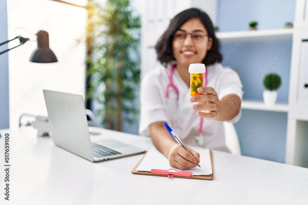 Young latin woman wearing doctor uniform prescribe pills at clinic Young latin woman wearing doctor uniform prescribe pills at clinic