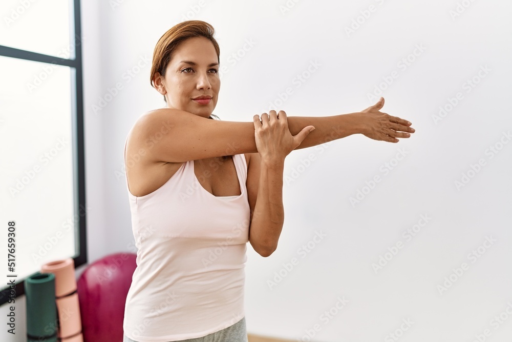 Young latin woman stretching at sport center Young latin woman stretching at sport center