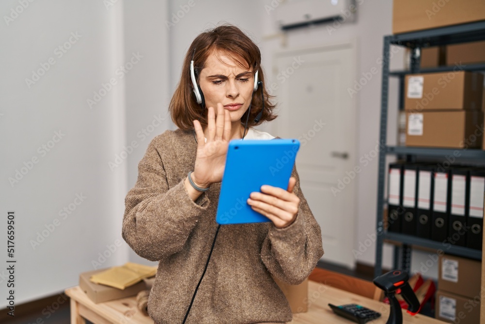 Young beautiful woman working at small business ecommerce with open hand doing stop sign with serious and confident expression, defense gesture Young beautiful woman working at small business ecommerce with open hand doing stop sign with serious and confident expression, defense gesture