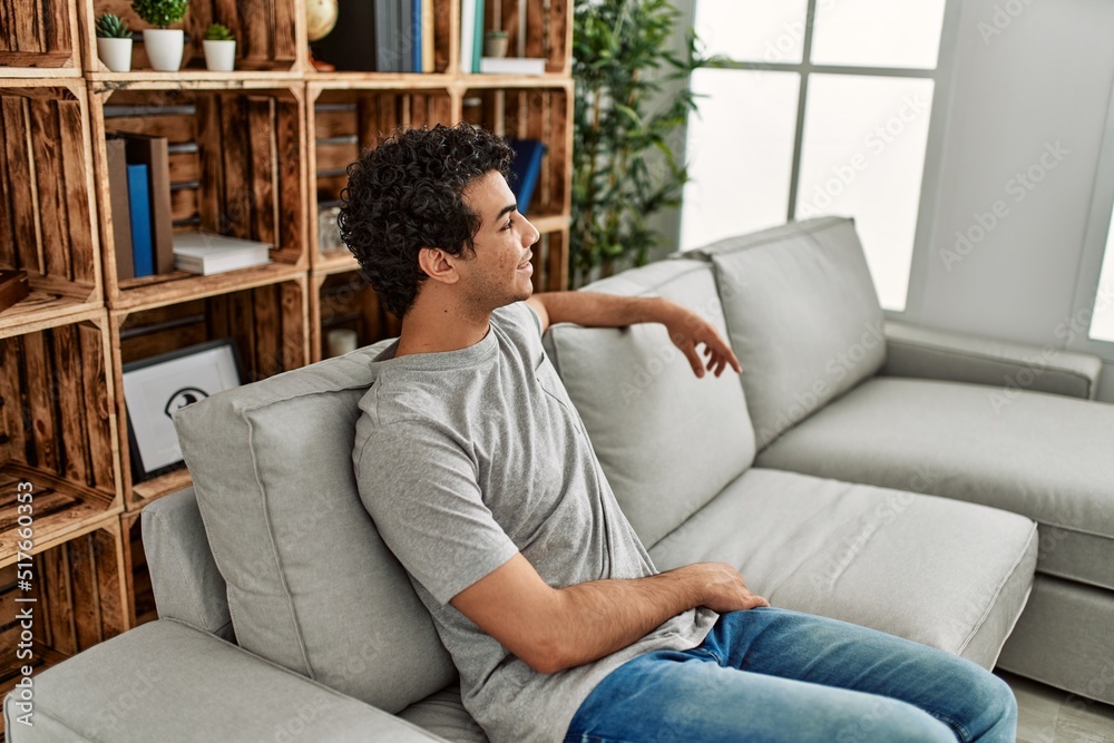 Obraz premium Young hispanic man smiling happy sitting on the sofa at home.