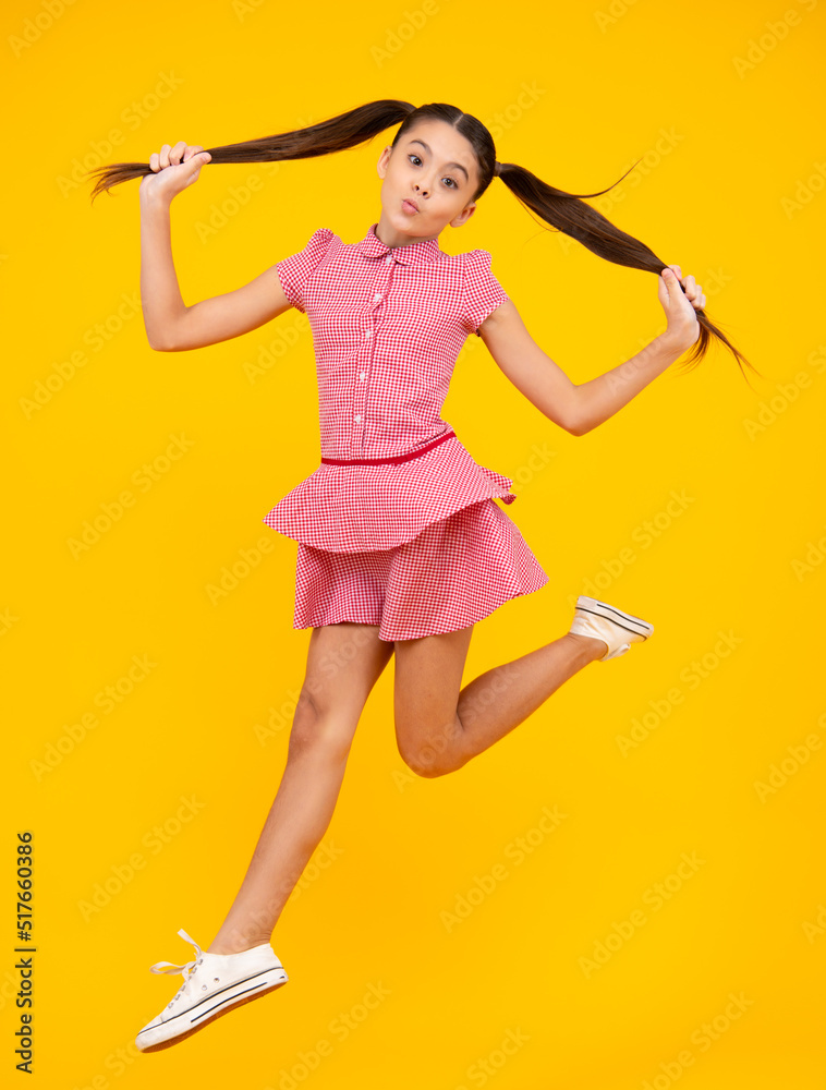 Amazed teenager. Teenager girl jumping. Full length of her she playful preteen teenager girl having fun and jumping isolated on yellow background. Excited teen girl. Amazed teenager. Teenager girl jumping. Full length of her she playful preteen teenager girl having fun and jumping isolated on yellow background. Excited teen girl.