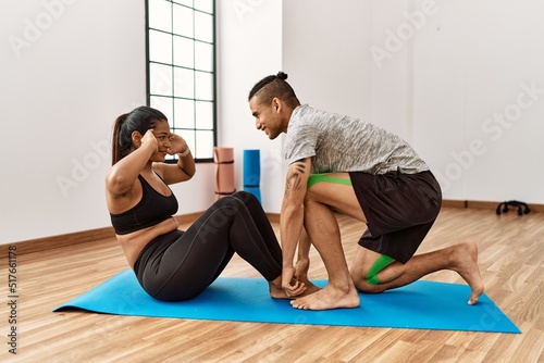 Young latin sporty couple smiling happy doing abs exercise at sport center.