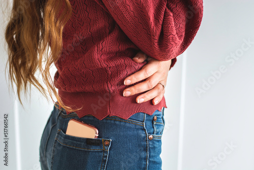Woman with long hair with mobile phone in the back pocket of her jeans. White background