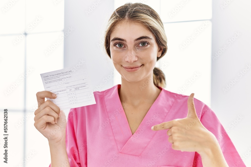 Young blonde woman holding covid record card pointing finger to one self smiling happy and proud Young blonde woman holding covid record card pointing finger to one self smiling happy and proud