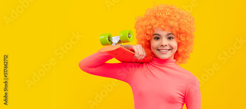 Happy girl child with orange hair in pink poloneck smile holding penny board  pennyboard. Funny teenager child on party  poster banner header with copy space.
