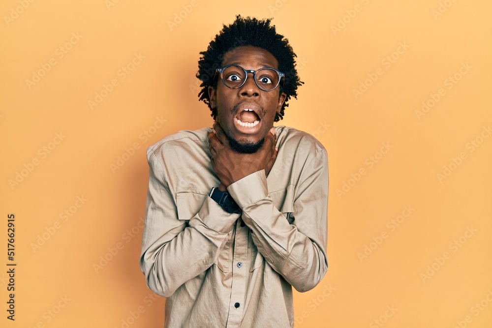 Young african american man wearing casual clothes and glasses shouting and suffocate because painful strangle. health problem. asphyxiate and suicide concept. Young african american man wearing casual clothes and glasses shouting and suffocate because painful strangle. health problem. asphyxiate and suicide concept.