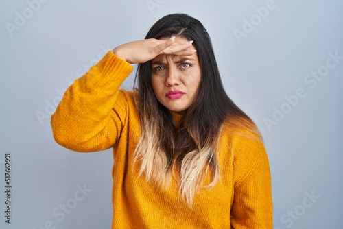 Young hispanic woman standing over isolated background worried and stressed about a problem with hand on forehead, nervous and anxious for crisis © Krakenimages.com