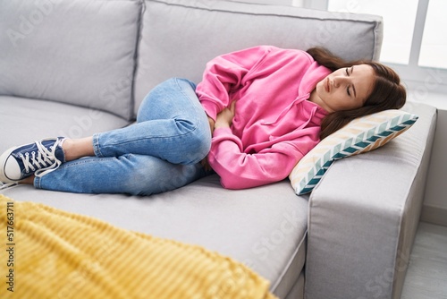 Young woman suffering for menstrual pain lying on sofa at home © Krakenimages.com