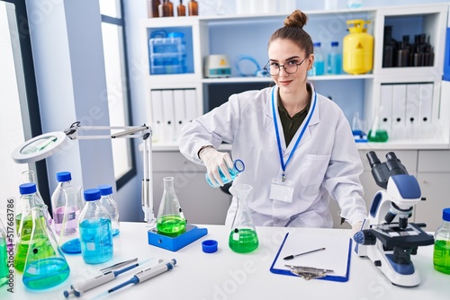 Young woman scientist measuring liquid at laboratory