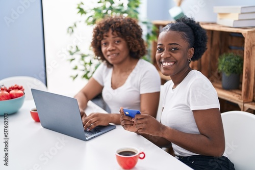 African american women mother and daughter using laptop and credit card at home