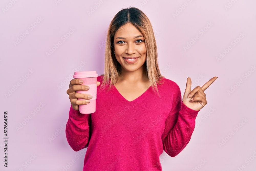 Beautiful hispanic woman drinking a take away cup of coffee smiling happy pointing with hand and finger to the side Beautiful hispanic woman drinking a take away cup of coffee smiling happy pointing with hand and finger to the side