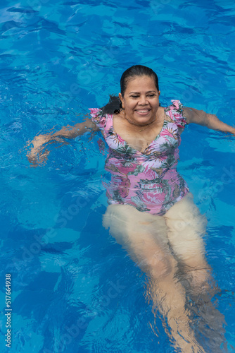 Older woman relaxing in the pool during the summer.