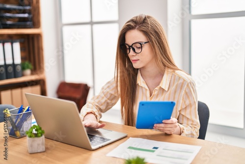 Young blonde woman business worker using laptop and touchpad working at office