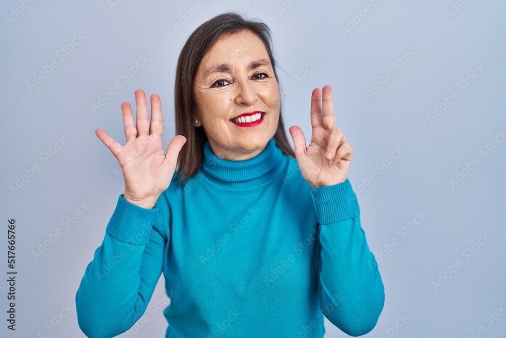 Middle age hispanic woman standing over isolated background showing and pointing up with fingers number eight while smiling confident and happy. Middle age hispanic woman standing over isolated background showing and pointing up with fingers number eight while smiling confident and happy.