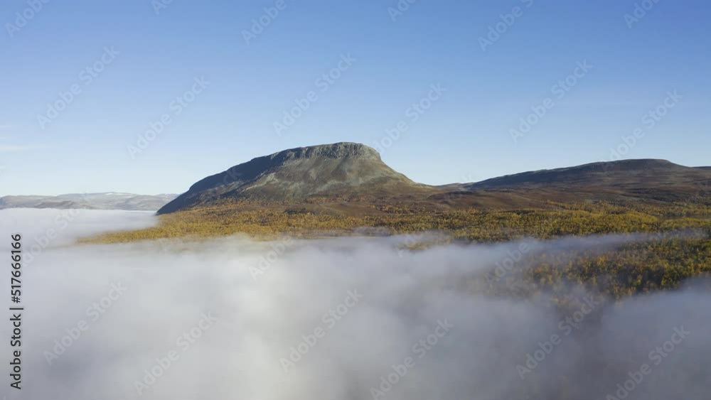 Thick mist and foggy landscape during a sunny day filmed from air with rocky mountain in the background. Thick mist and foggy landscape during a sunny day filmed from air with rocky mountain in the background.