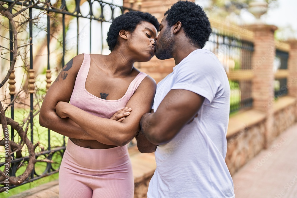 African american man and woman sporty couple standing with arms crossed gesture and kissing at street African american man and woman sporty couple standing with arms crossed gesture and kissing at street