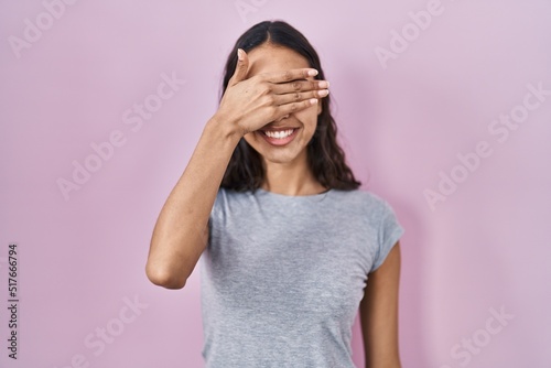 Young brazilian woman wearing casual t shirt over pink background smiling and laughing with hand on face covering eyes for surprise. blind concept. © Krakenimages.com