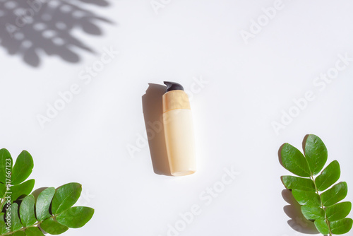 Cosmetic bottle with green leaf and shadow light effec on white background