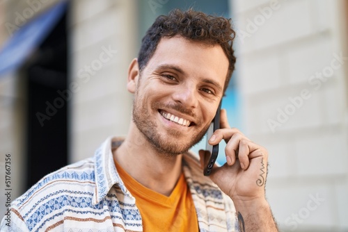 Young hispanic man smiling confident talking on the smartphone at street