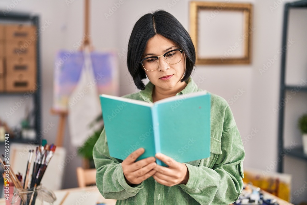 Young chinese woman artist reading book at art studio Young chinese woman artist reading book at art studio